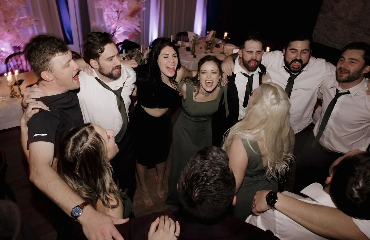 Wedding guests with their arms around each other singing in a circle at the Jackson wedding in Reykjavik, Iceland