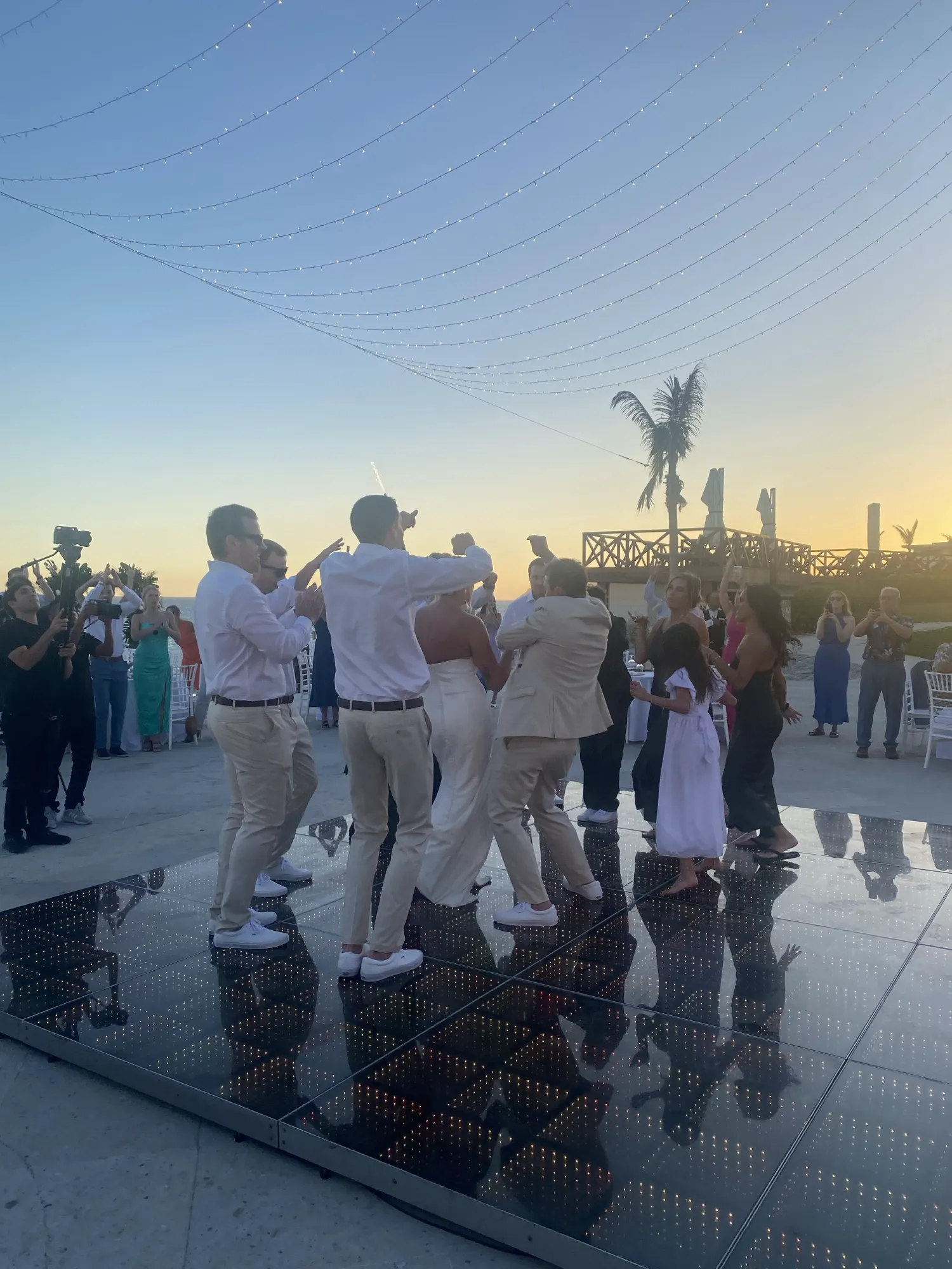 Guests dancing on a lit-up dance floor at sunset at a resort wedding in Mexico