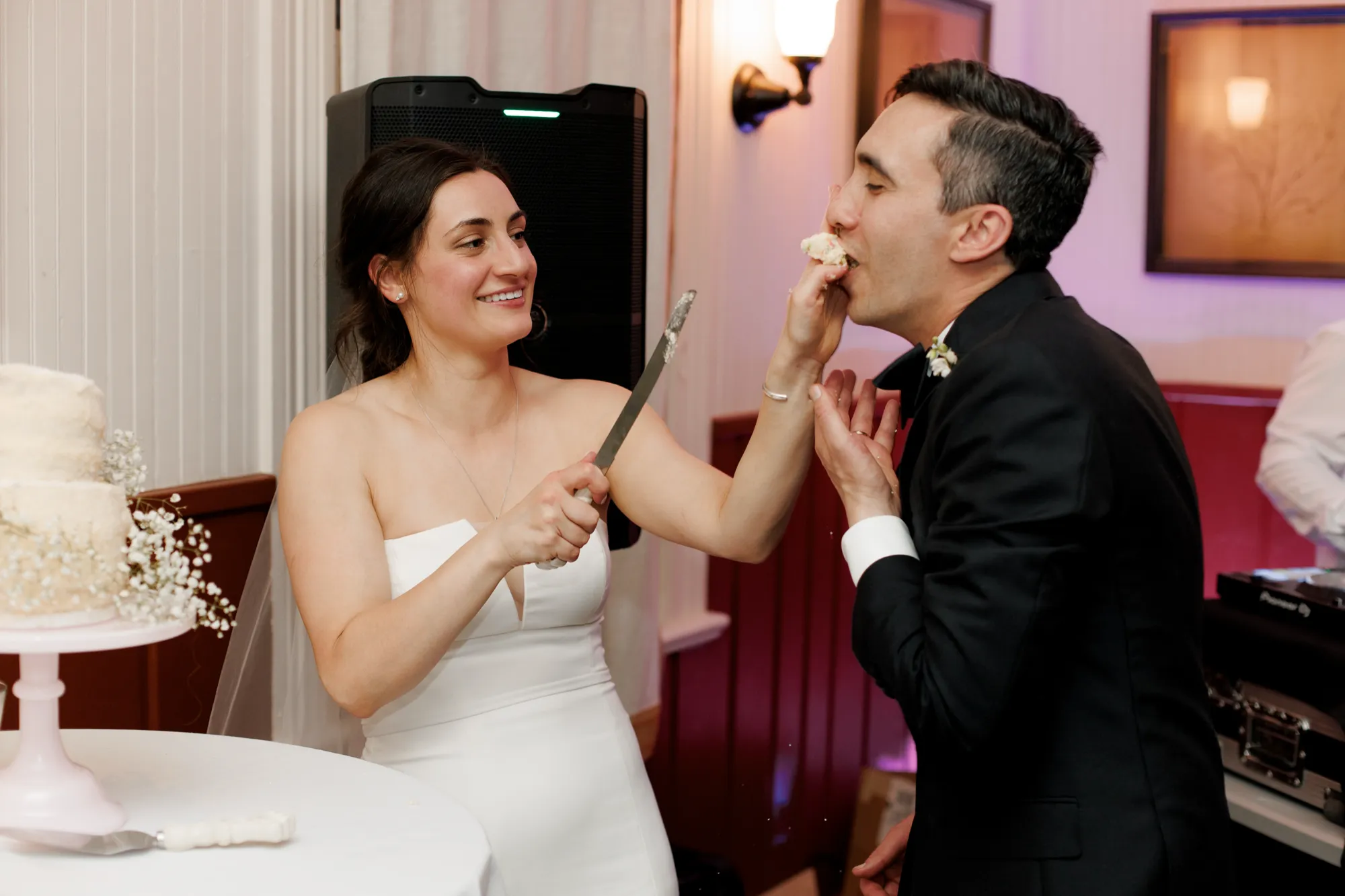 The bride and groom share cake with the DJ setup behind them at Chautauqua in Boulder