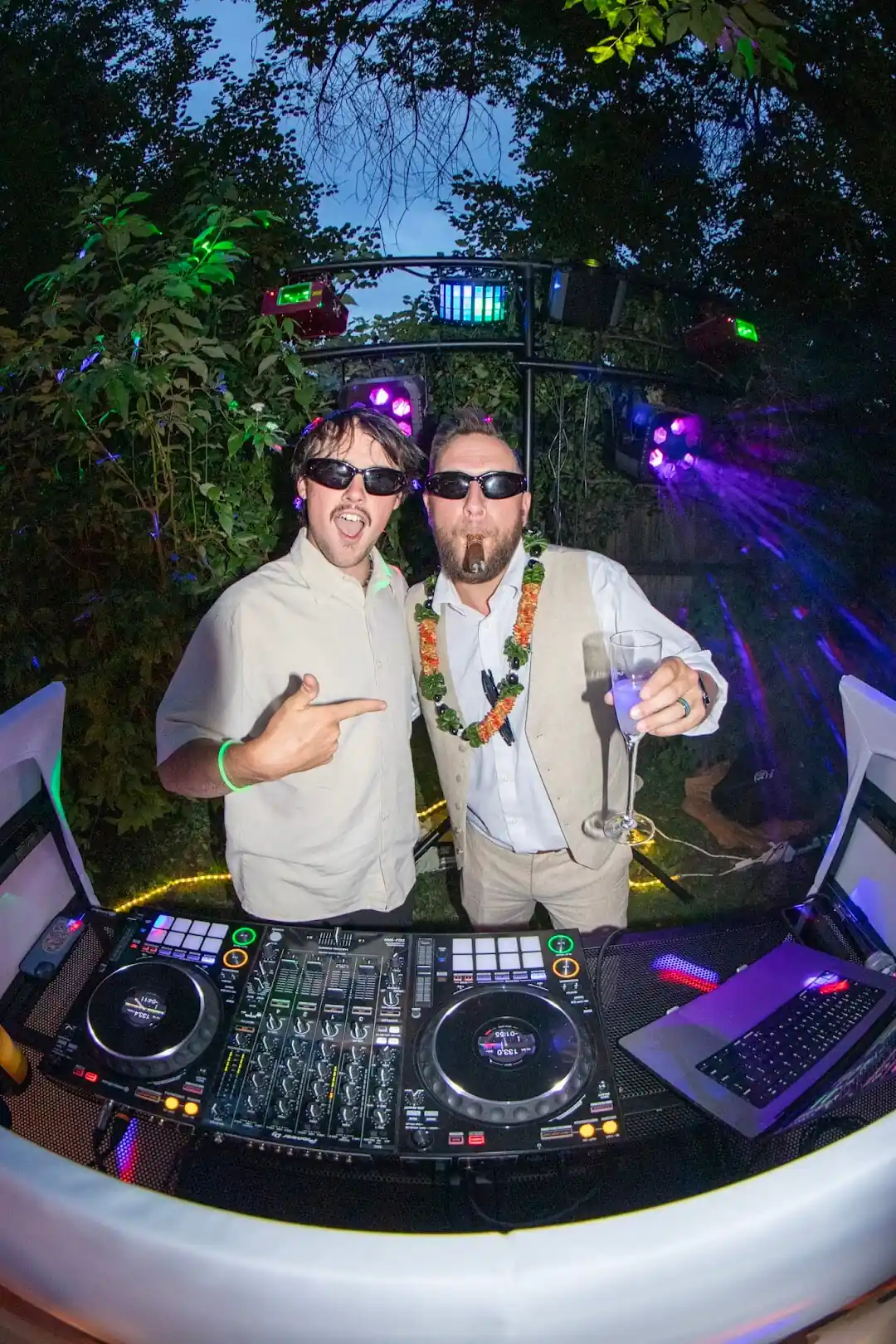 Two guests celebrating behind the DJ booth with a cigar and champagne at the Torrison wedding in Lakewood, Colorado
