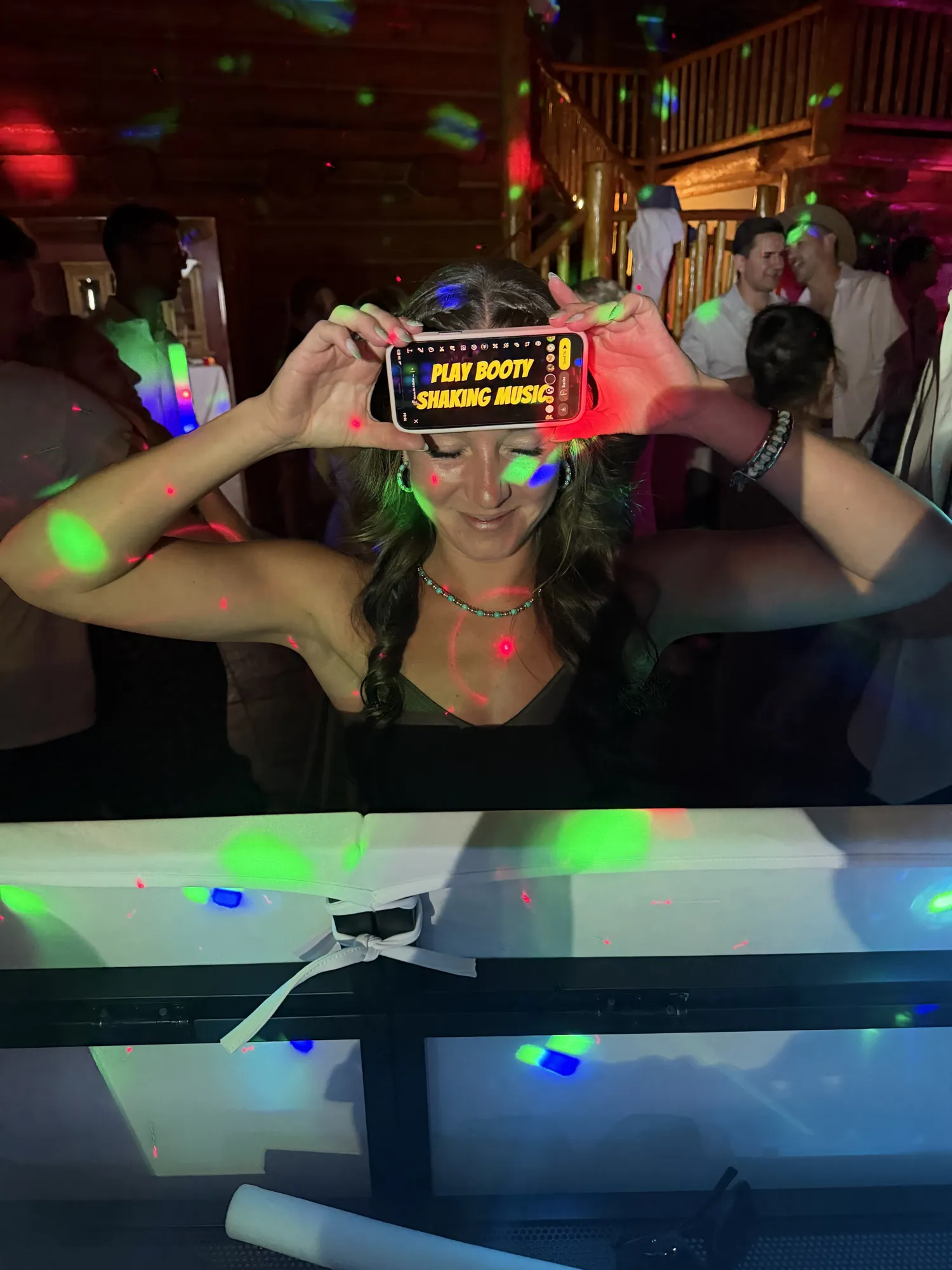 A wedding guest holds up a phone asking the DJ to play booty-shaking music